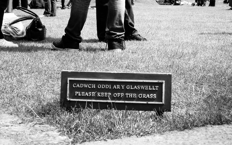 7939960670_a8e868c71f_c Feet on a lawn behind a sign reading "Please keep off the grass"